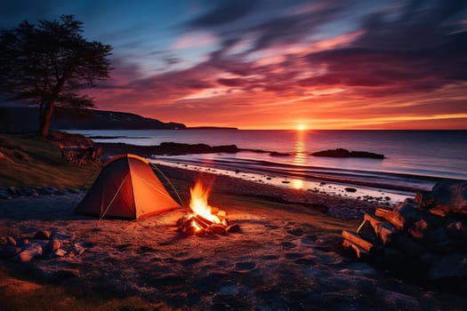 Camping by the sea. Tent and fire at sunset.