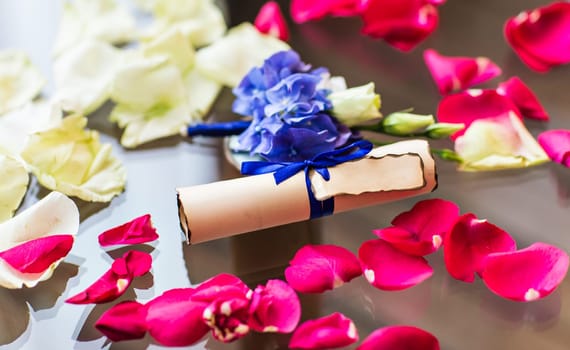 scroll paper on the table. rose petals