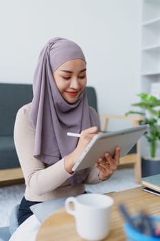 Female Muslim employee uses tablet to work at office