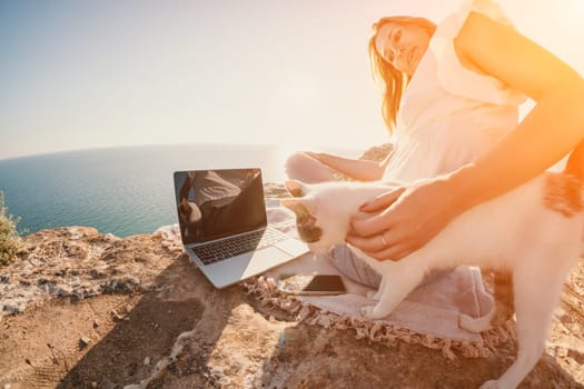 Woman sea laptop. Business woman in yellow hat working on laptop by sea. Close up on hands of pretty lady typing on computer outdoors summer day. Freelance, digital nomad, travel and holidays concept.