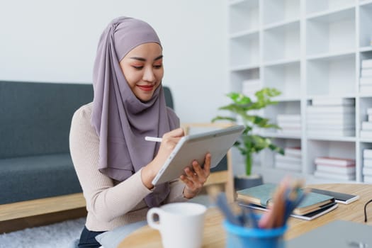 Female Muslim employee uses tablet to work at office