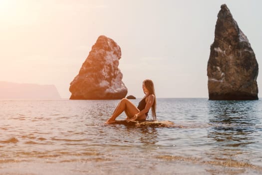 Woman travel sea. Young Happy woman in a long red dress posing on a beach near the sea on background of volcanic rocks, like in Iceland, sharing travel adventure journey