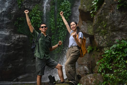 Young couple tourist raising hand to celebrating achievement, success and goal in forest.