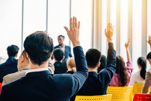 A boardroom strategy session unfolds with businesspeople in a meeting and seminar. Raised hands signify questions highlighting collaboration among colleagues and employees.