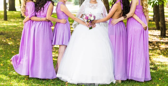 Bride with bridesmaids on the park on the wedding day