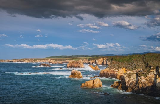 View of cliffs on the Asturian coast on a sunny day with blue sky and some clouds in the sky.