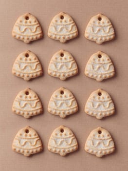 Freshly baked homemade bell-shaped sugar christmas cookies on the craft background, vertical