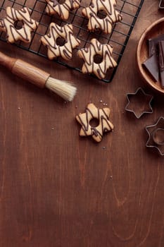 Freshly baked homemade star-shaped cookie with chocolate on the grid on the wooden table with a copy space, vertical