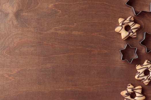 Freshly baked homemade star-shaped cookie with chocolate with cutters on the wooden table with a copy space, horizontal banner