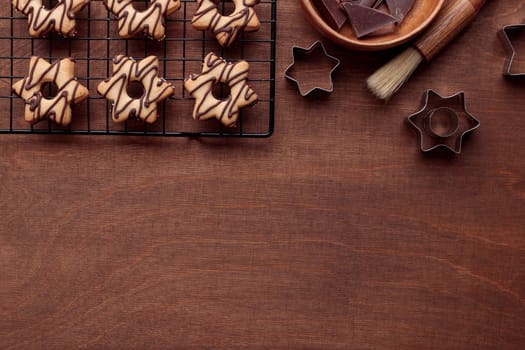 Freshly baked homemade star-shaped cookie with chocolate on the grid on the wooden table with a copy space, horizontal banner