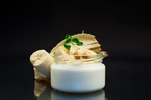 home sweet banana yogurt in a glass jar isolated on black background