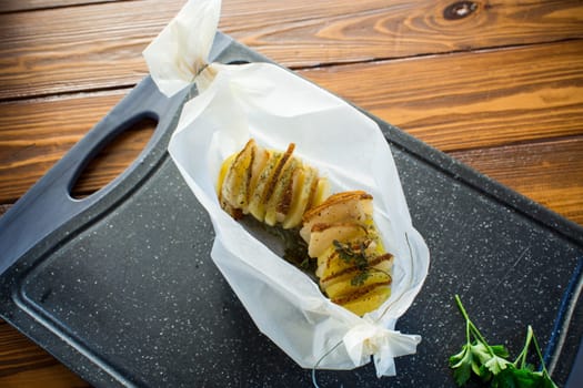 Baked potatoes stuffed with lard and spices in baking paper.