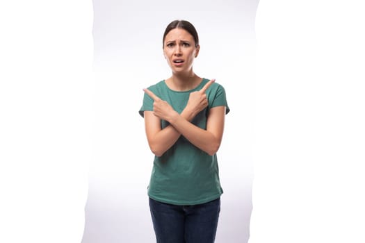 young beautiful brunette lady dressed in a green t-shirt and jeans crossed her arms in disagreement.