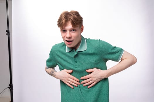 young cheerful red-haired man dressed in a green t-shirt laughs at a joke on the background with copy space.