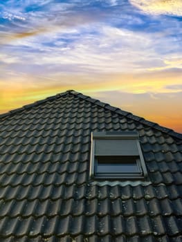 Open roof window in velux style with black roof tiles