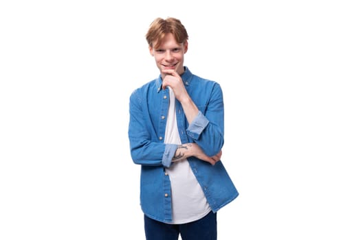 portrait of a smiling caucasian red-haired guy in a denim blue denim shirt on a studio background.