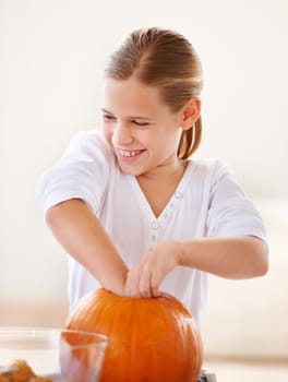 Hollowing out a pumpkin for a jack-o-lantern. A little girl hollowing out a pumpkin in her kitchen for halloween