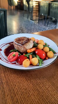 Beef steak with salad. Potato balls and various vegetables on a colored plate. Meat restaurant