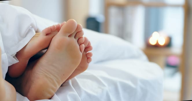 Feet, love and a couple sleeping in bed together for romance or bonding in their home in the morning. Relax, dating or playful with a man and woman barefoot in the bedroom of their apartment closeup.