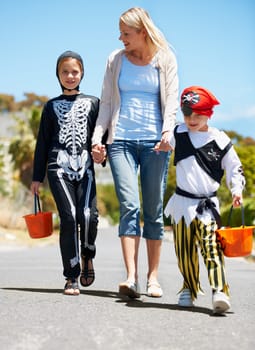 Going trick or treating. Children in costume going treat or treating with their mom