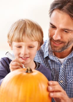 Ill carve it after you mark out the face. A father and son marking a pumpkin in the kitchen for halloween