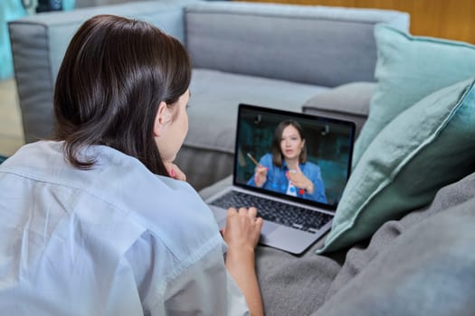 Laptop screen video call conference online chat webinar, young woman talking. Female lying on sofa listening looking at computer. Remote work learning training education influencer blogger vlogger job