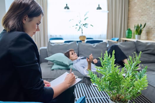 Middle-aged woman at meeting with psychologist counselor, sitting on couch in office. Mental problems of age female, psychological support help. Psychology psychotherapy therapy treatment healthcare