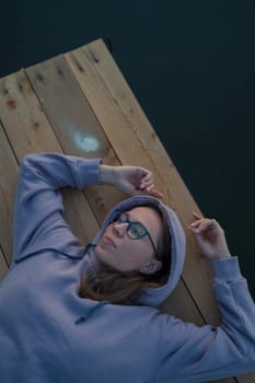 Woman lying down on the pier at lake, closeup portrait, summer sunset