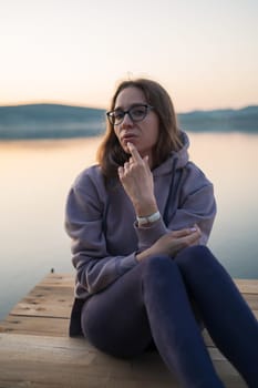 Woman sitting on the pier, closeup portrait, summer sunset