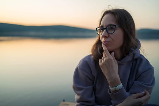 Woman sitting on the pier, closeup portrait, summer sunset