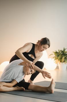 Mom and teenage daughter do gymnastics together in the fitness room. A woman and a girl train in the gym.