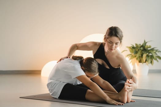 Mom and teenage daughter do gymnastics together in the fitness room. A woman and a girl train in the gym.