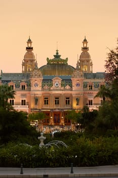 Monaco, Monte-Carlo, 12 November 2022: The famous square of Casino Monte-Carlo is at dusk, attraction night illumination, luxury cars, players, tourists, splashes of fountain. High quality photo