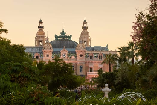 Monaco, Monte-Carlo, 12 November 2022: The famous square of Casino Monte-Carlo is at dusk, attraction night illumination, luxury cars, players, tourists, splashes of fountain. High quality photo