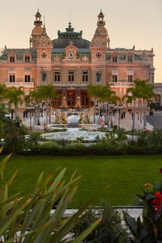 Monaco, Monte-Carlo, 12 November 2022: The famous square of Casino Monte-Carlo is at dusk, attraction night illumination, luxury cars, players, tourists, splashes of fountain. High quality photo