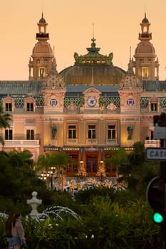 Monaco, Monte-Carlo, 12 November 2022: The famous square of Casino Monte-Carlo is at dusk, attraction night illumination, luxury cars, players, tourists, splashes of fountain. High quality photo