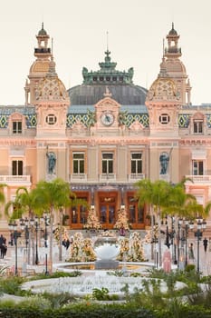 Monaco, Monte-Carlo, 12 November 2022: The famous square of Casino Monte-Carlo is at dusk, attraction night illumination, luxury cars, players, tourists, splashes of fountain. High quality photo