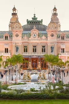 Monaco, Monte-Carlo, 12 November 2022: The famous square of Casino Monte-Carlo is at dusk, attraction night illumination, luxury cars, players, tourists, splashes of fountain. High quality photo