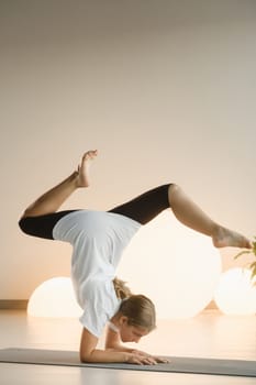 A teenage girl in sports clothes does yoga in a fitness room.