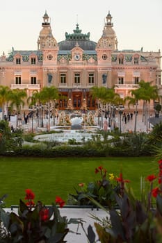 Monaco, Monte-Carlo, 12 November 2022: The famous square of Casino Monte-Carlo is at dusk, attraction night illumination, luxury cars, players, tourists, splashes of fountain. High quality photo