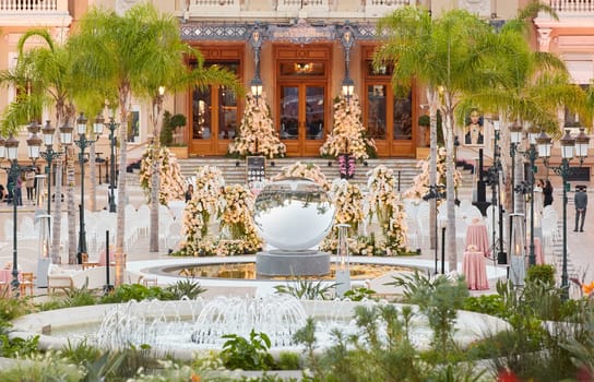 Monaco, Monte-Carlo, 12 November 2022: The famous square of Casino Monte-Carlo is at dusk, attraction night illumination, luxury cars, players, tourists, splashes of fountain. High quality photo