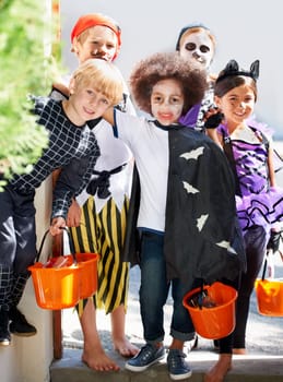 Our pales are full of candy. Portrait of a group of little children trick-or-treating on halloween