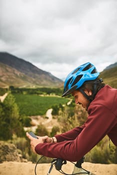 Technology takes him places. a young man using his cellphone while cycling along a trail