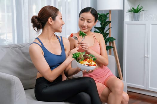 Young sporty Asian women in sportswear holding salad bowl together fill with vibrant of fruit and vegetable. Natural youthful and fit body lifestyle with balance nutrition and home exercise. Vigorous