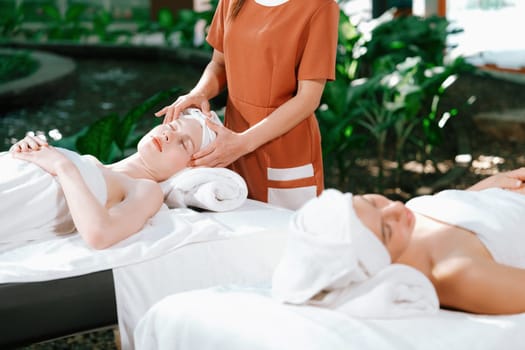 A portrait of two caucasian woman with beautiful skin having facial massage while falling the deep state of relaxation surrounded by outdoor natural and peaceful environment. Tranquility.