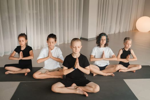 Children sit on mats in the lotus position in Yoga classes. Children's yoga.