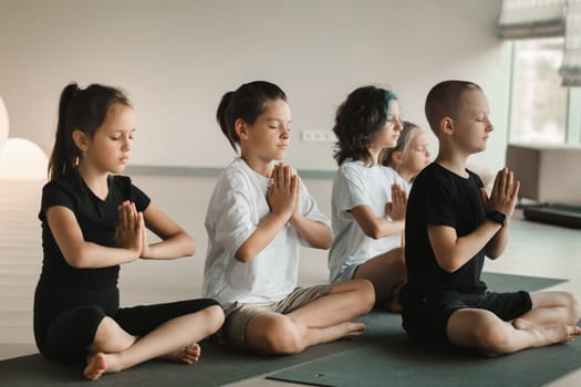 Children sit on mats in the lotus position in Yoga classes. Children's yoga.