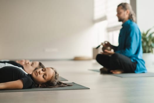 Children relax lying down to the sounds of a Tibetan bowl in the fitness room. Children's yoga.