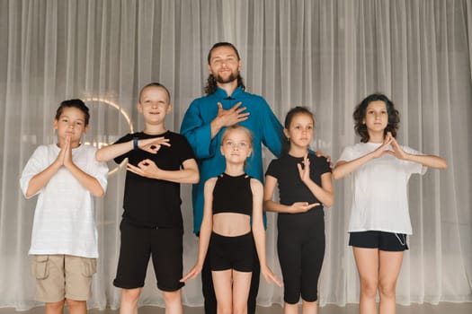 A joint portrait of a yoga coach and children standing in a fitness room.