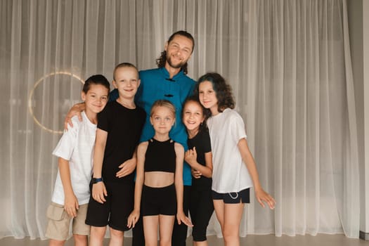 A joint portrait of a yoga coach and children standing in a fitness room.